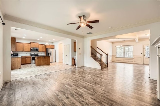 unfurnished living room with light wood-style flooring, crown molding, stairs, visible vents, and ceiling fan with notable chandelier