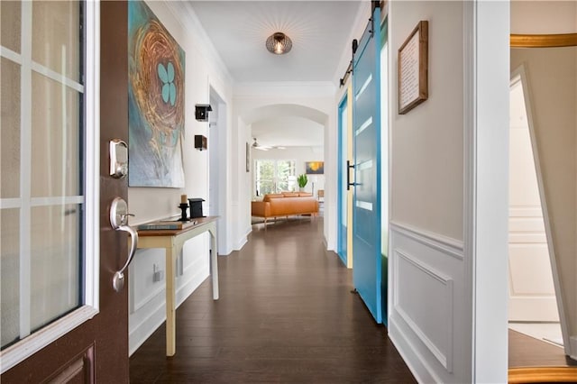 corridor featuring a barn door, dark hardwood / wood-style floors, and crown molding