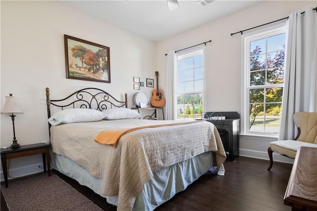 bedroom with dark hardwood / wood-style floors and multiple windows