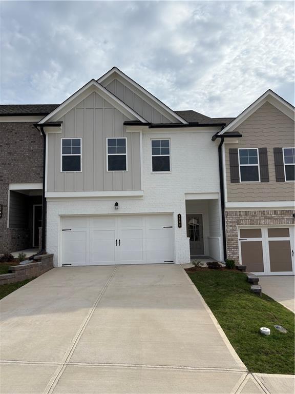 view of front of home with concrete driveway, an attached garage, board and batten siding, and brick siding