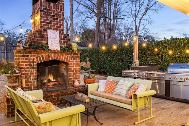 patio terrace at dusk with an outdoor brick fireplace, grilling area, and an outdoor kitchen