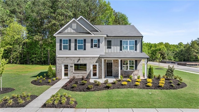 view of front of property with a front yard, brick siding, board and batten siding, and covered porch