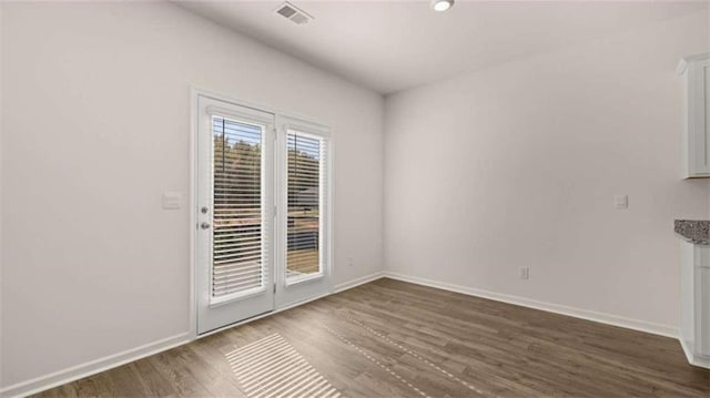 unfurnished dining area featuring visible vents, dark wood-style flooring, and baseboards
