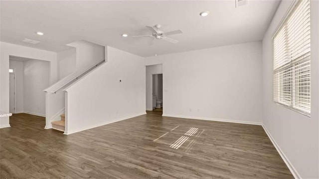 unfurnished living room featuring a ceiling fan, stairs, wood finished floors, and a healthy amount of sunlight