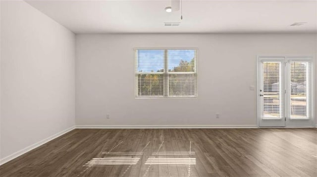 empty room featuring visible vents, baseboards, and wood finished floors