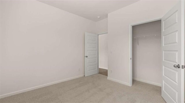 unfurnished bedroom with light carpet, a closet, and baseboards