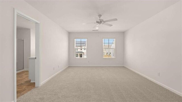 unfurnished room featuring light colored carpet, baseboards, and ceiling fan