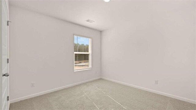 unfurnished room with carpet, visible vents, and baseboards