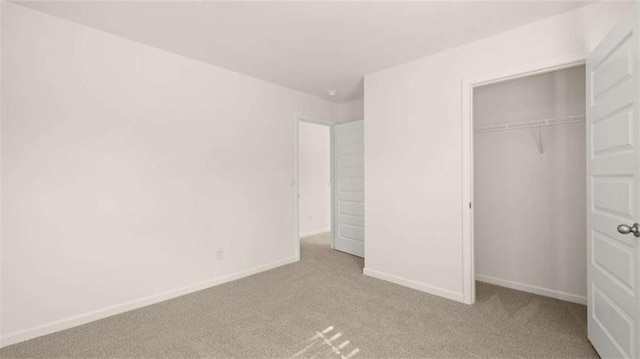 unfurnished bedroom with light colored carpet and a closet