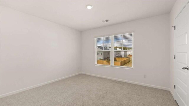 spare room with light carpet, visible vents, and baseboards