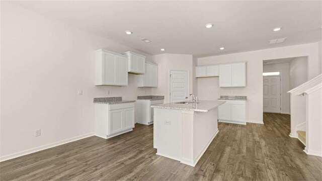 kitchen featuring baseboards, dark wood-style floors, white cabinetry, a center island with sink, and a sink