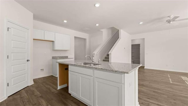 kitchen with ceiling fan, an island with sink, white cabinets, dark wood-style flooring, and a sink