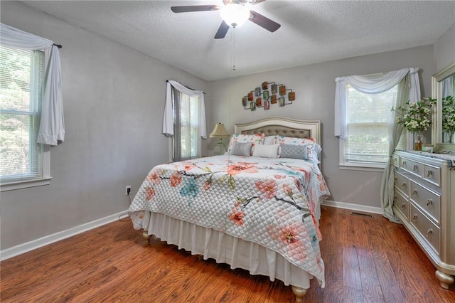 bedroom with dark wood-type flooring, multiple windows, ceiling fan, and a textured ceiling