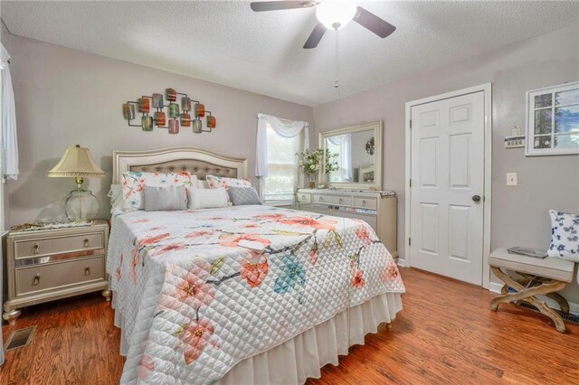 bedroom with a textured ceiling, ceiling fan, and hardwood / wood-style floors