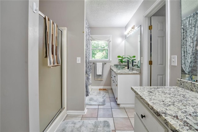 bathroom with a shower with shower door, tile patterned flooring, a textured ceiling, and vanity