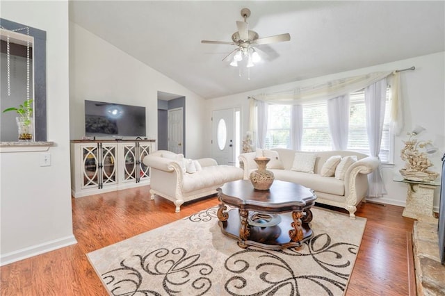 living room featuring lofted ceiling, ceiling fan, wood finished floors, and baseboards