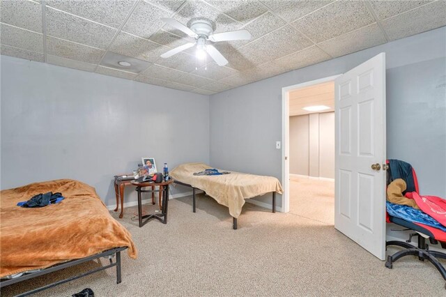 carpeted bedroom with a paneled ceiling and ceiling fan