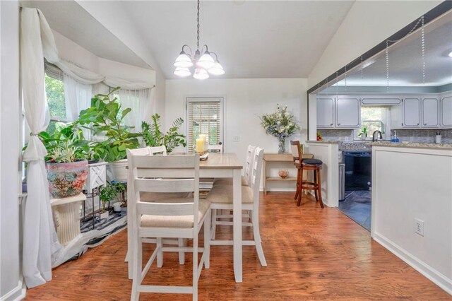 dining area with lofted ceiling, wood-type flooring, and a notable chandelier