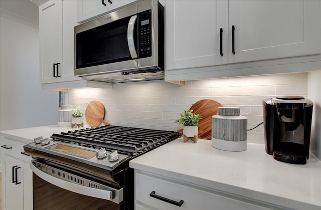 kitchen with backsplash, appliances with stainless steel finishes, white cabinets, and light countertops