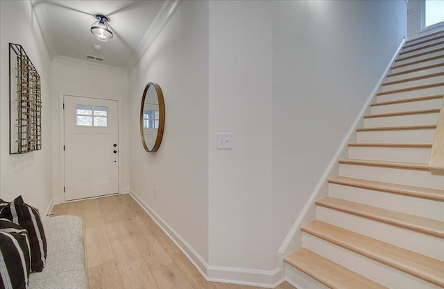 foyer featuring visible vents, crown molding, baseboards, stairway, and light wood-style floors