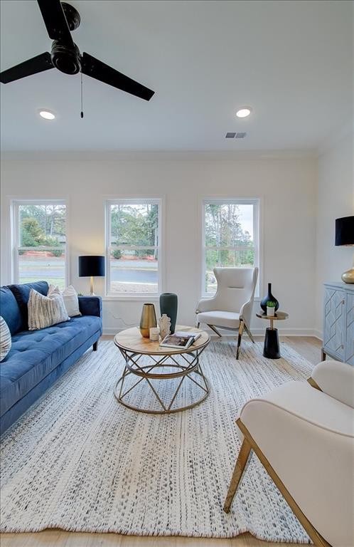 living room featuring visible vents, crown molding, baseboards, recessed lighting, and a ceiling fan