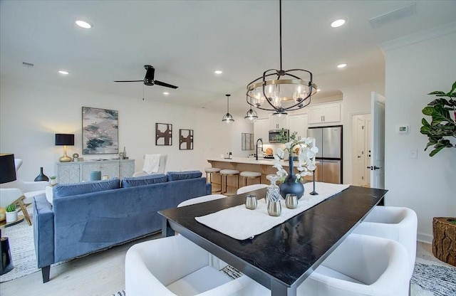 dining room with light wood finished floors, recessed lighting, ceiling fan with notable chandelier, and crown molding