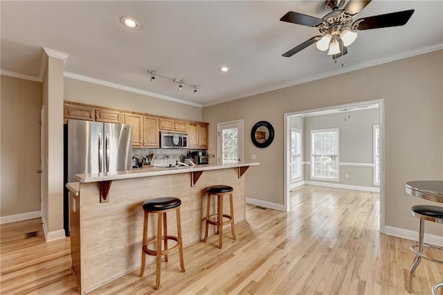 39 Legendary Dr, Hoschton, GA 30548 - kitchen with appliances with stainless steel finishes, crown molding, a kitchen bar, light countertops, and tasteful backsplash