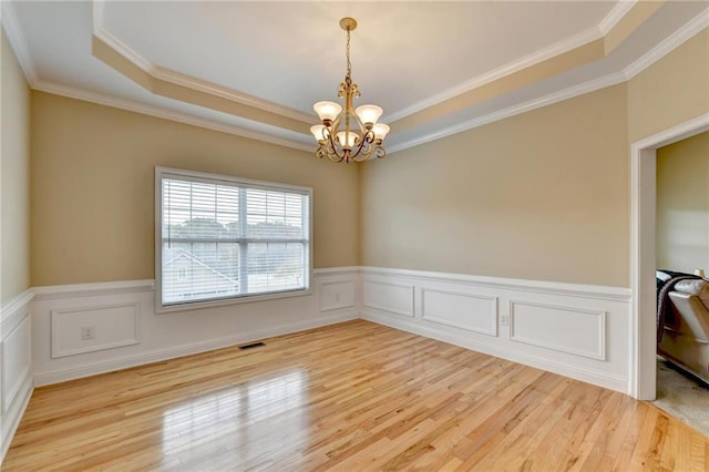 39 Legendary Dr, Hoschton, GA 30548 - empty room with light wood-type flooring, a chandelier, a wainscoted wall, crown molding, and a raised ceiling
