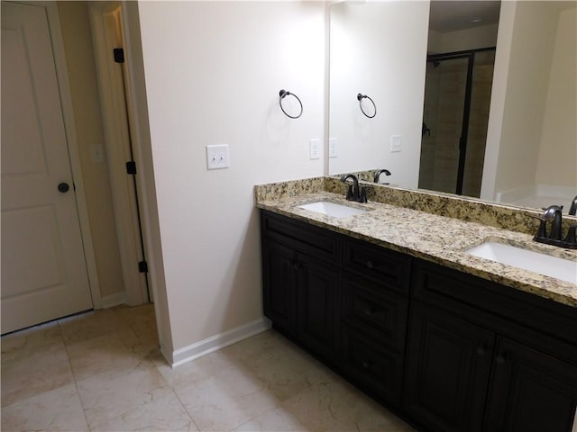 full bath featuring marble finish floor, a shower stall, baseboards, and a sink