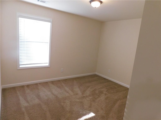 spare room featuring carpet flooring, visible vents, and baseboards