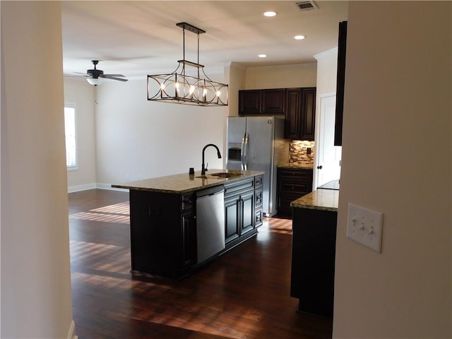 kitchen with appliances with stainless steel finishes, stone countertops, dark wood finished floors, and backsplash