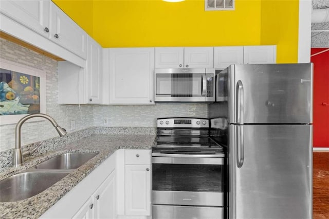 kitchen with backsplash, appliances with stainless steel finishes, sink, and white cabinetry