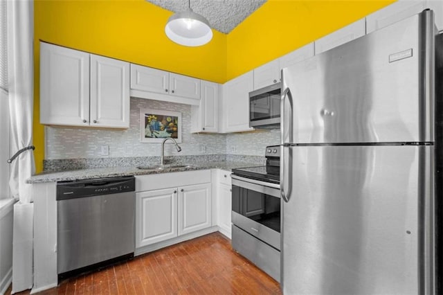 kitchen featuring decorative backsplash, white cabinetry, appliances with stainless steel finishes, hardwood / wood-style flooring, and sink