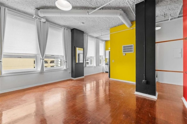 empty room with a textured ceiling and wood-type flooring