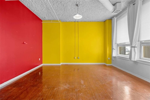 unfurnished room with wood-type flooring and a textured ceiling