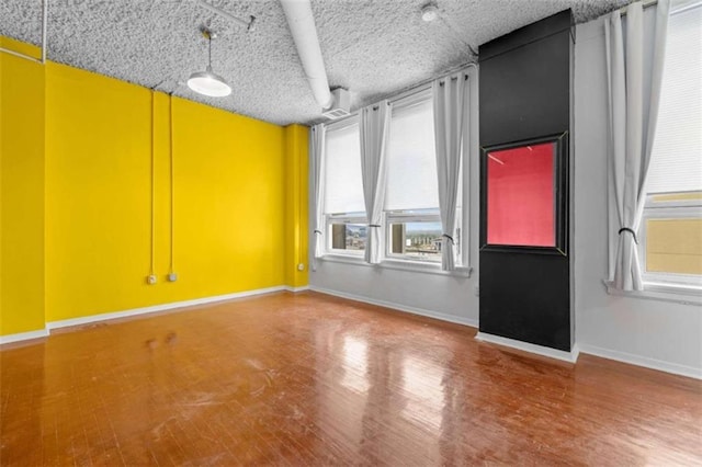 spare room featuring a textured ceiling and hardwood / wood-style floors