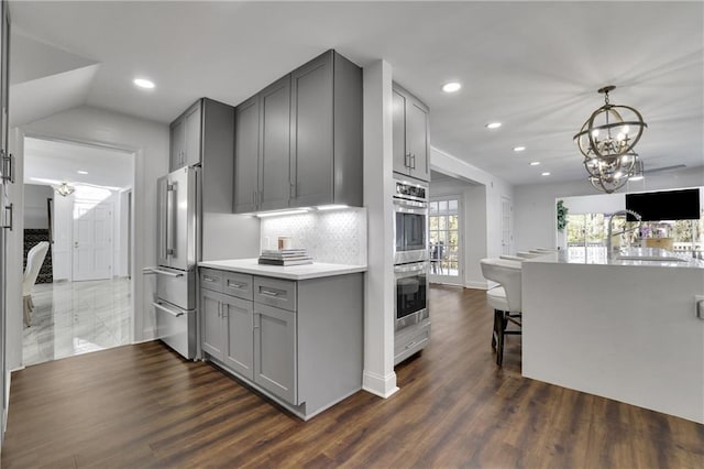 kitchen with gray cabinets, appliances with stainless steel finishes, dark hardwood / wood-style flooring, and decorative backsplash