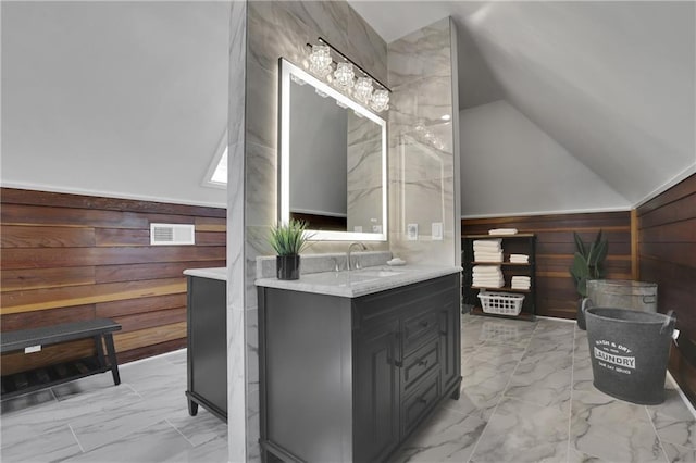 bathroom featuring lofted ceiling, vanity, and wood walls