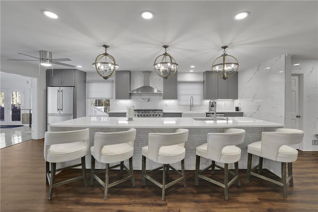 kitchen featuring high end fridge, hanging light fixtures, dark hardwood / wood-style flooring, gray cabinets, and wall chimney range hood