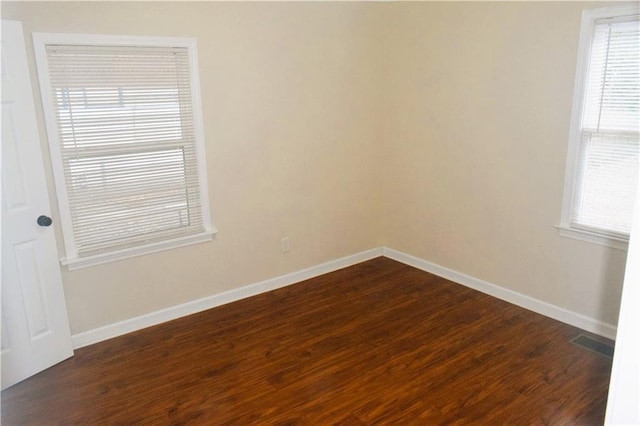 spare room featuring dark wood-type flooring and a healthy amount of sunlight