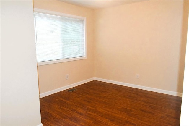 unfurnished room featuring dark wood-type flooring and plenty of natural light