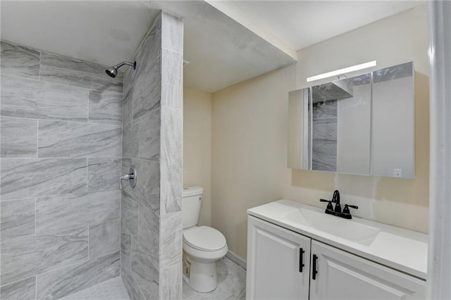 bathroom with toilet, vanity, and a tile shower