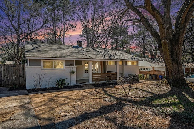 view of front of property with covered porch, fence, and brick siding