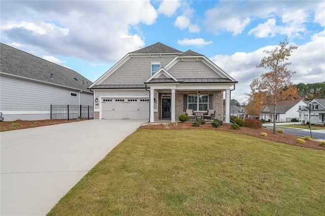 craftsman-style home with covered porch, a garage, driveway, a standing seam roof, and a front yard