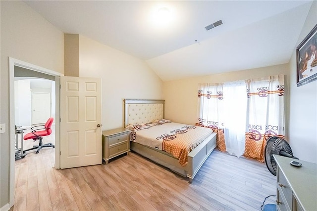 bedroom with lofted ceiling, light wood finished floors, arched walkways, and visible vents