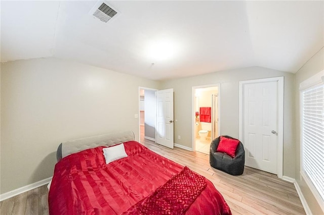 bedroom with baseboards, visible vents, vaulted ceiling, and wood finished floors