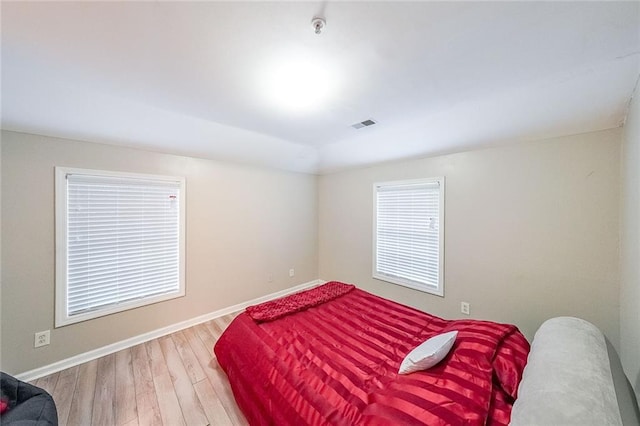 bedroom featuring visible vents, baseboards, and wood finished floors