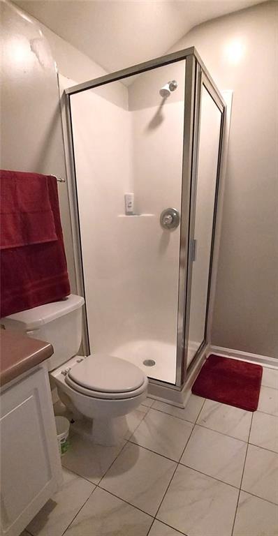 full bathroom with a stall shower, vanity, and toilet