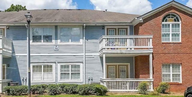 rear view of property featuring covered porch, brick siding, and a balcony