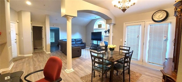 dining space with lofted ceiling, arched walkways, light wood-style flooring, and ornate columns